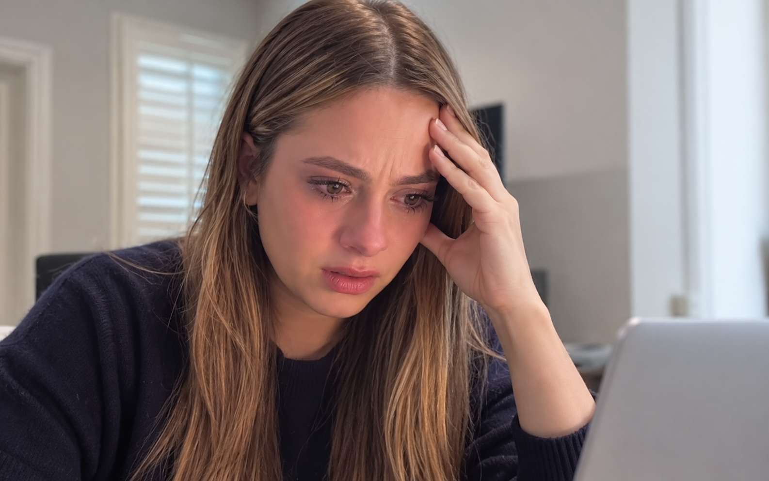 A woman looking concerned while using her laptop